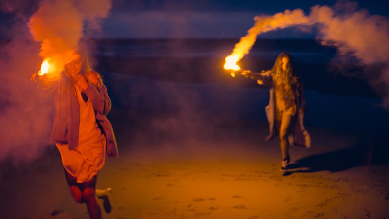 two people with fire-lit torches in the dark